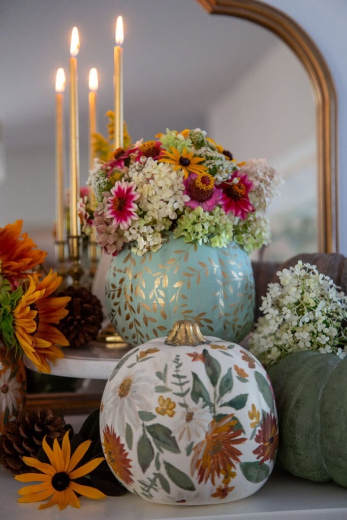 Blue painted pumpkin used as a vase for floral arrangement with hydrangeas, zinnias, and wildflowers.