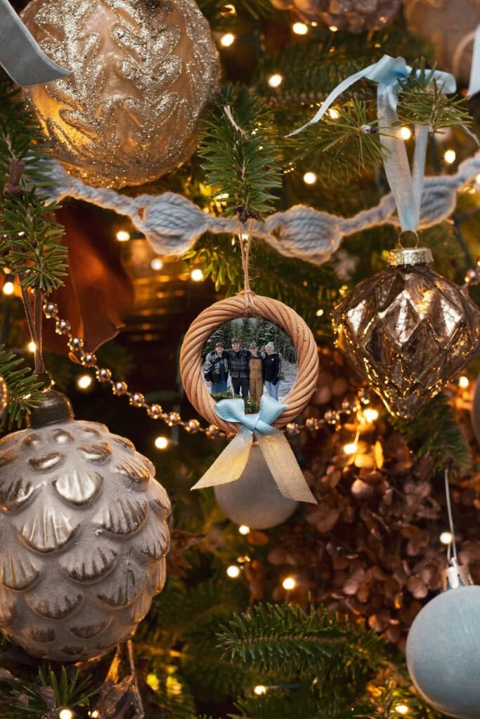 Finished easy DIY photo ornament hanging on a Christmas tree with lights.