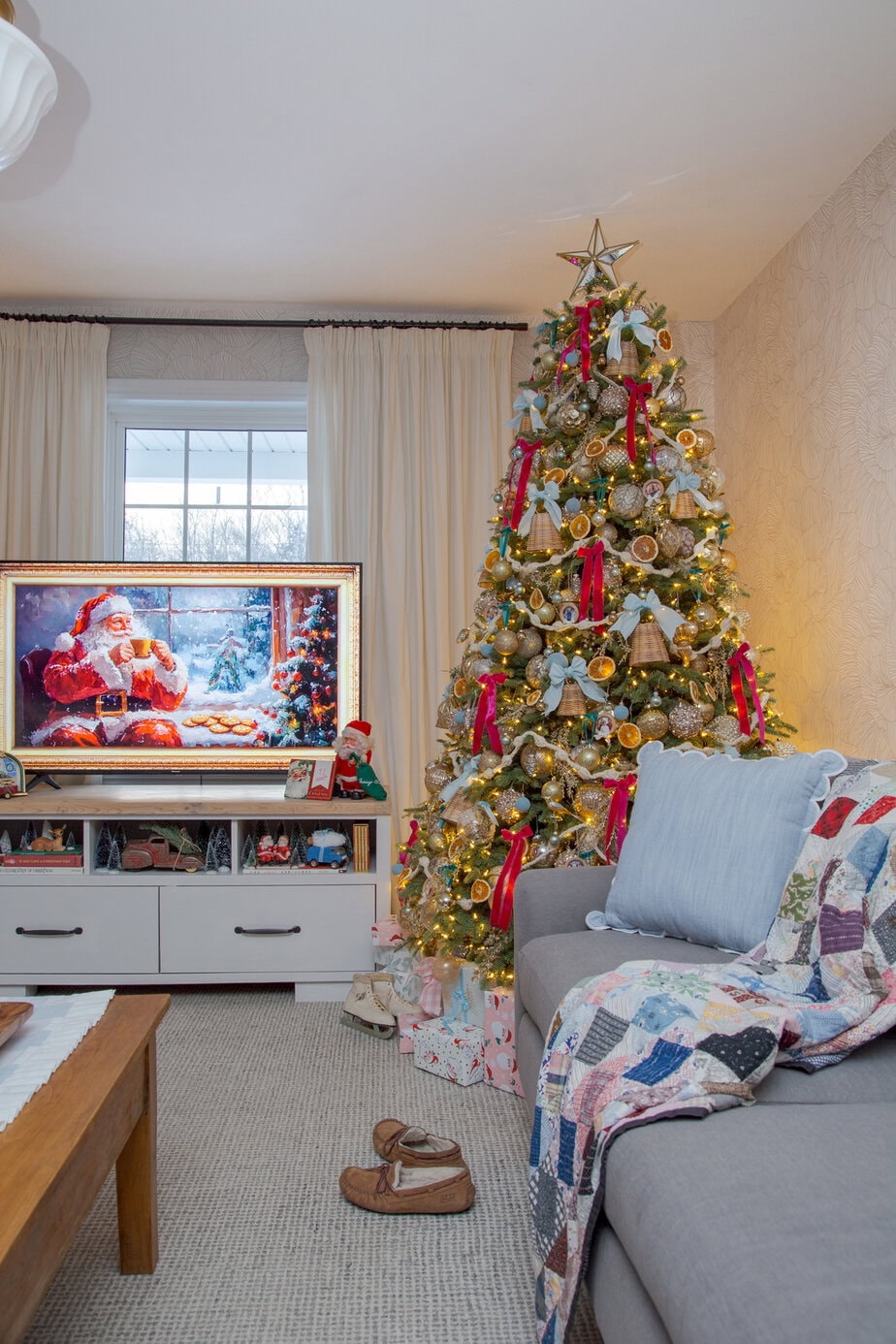 Vintage Christmas tree with gold ornaments, dried orange slices, and red and blue ribbon bows in a cozy living room.